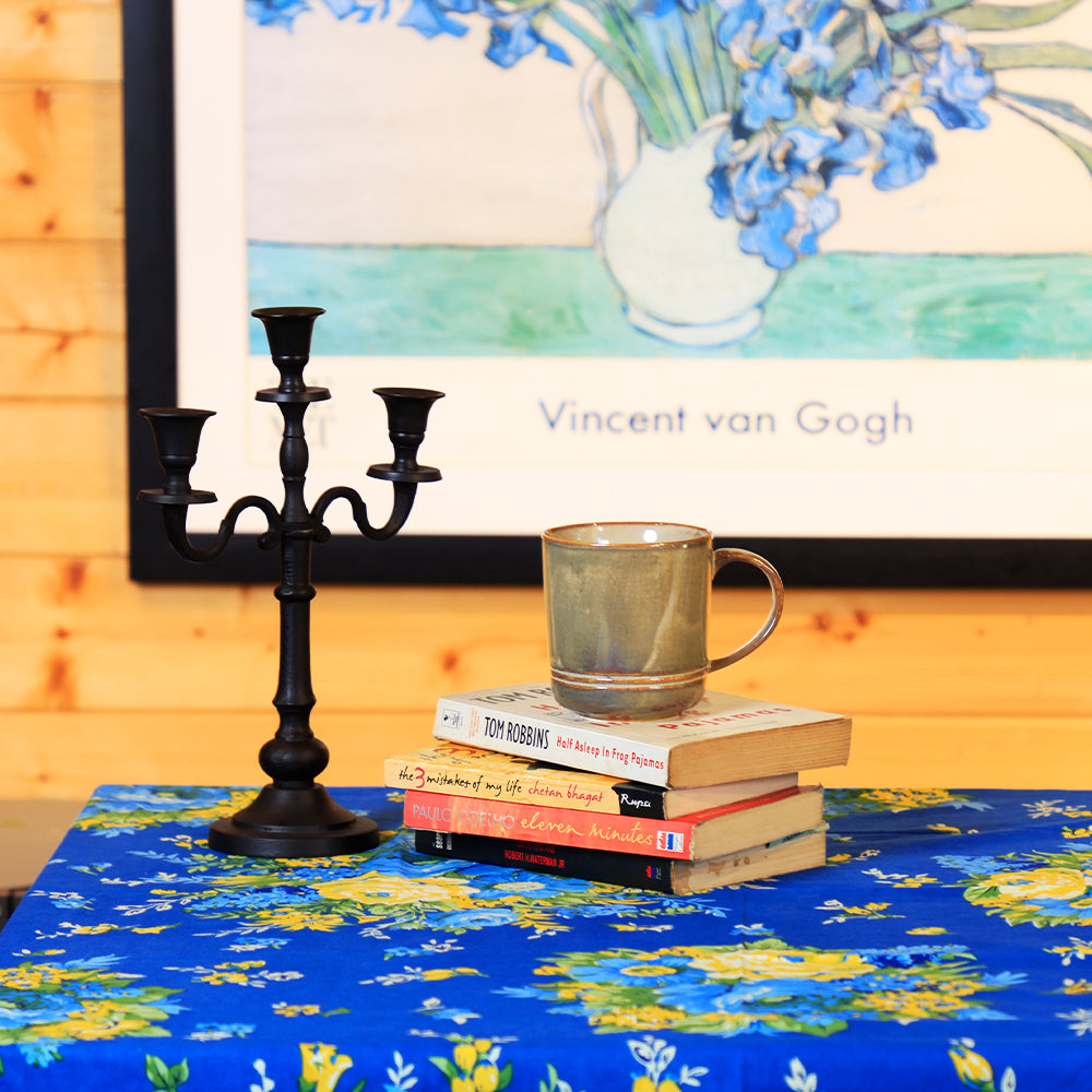 Yellow Marigold Matte Edit three‑stick metal candle holder placed on a wooden dining table with lit candles — warm ambient home décor setup