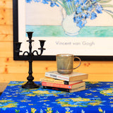 Yellow Marigold Matte Edit three‑stick metal candle holder placed on a wooden dining table with lit candles — warm ambient home décor setup